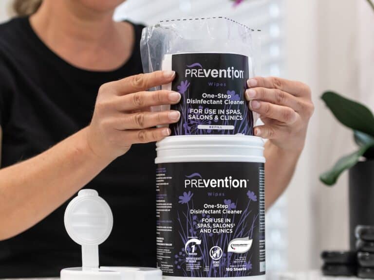 Beauty professional refilling a Prevention Disinfectant Wipes canister with a refill pouch